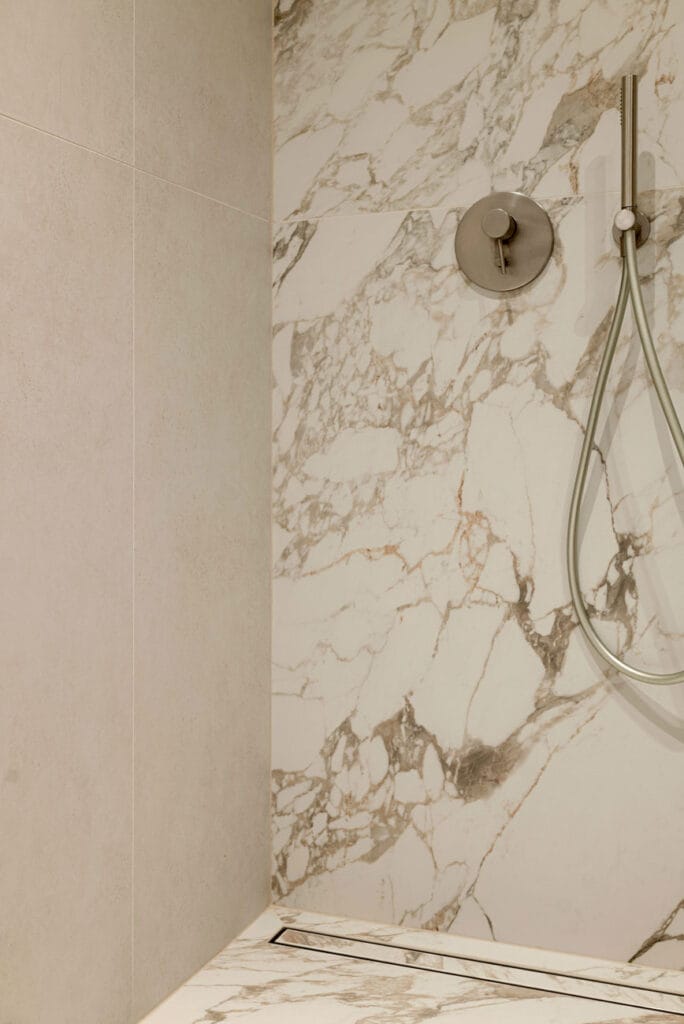 Nowoczesna kabina prysznicowa z luksusowymi marmurowymi płytkami i elegancznym systemem prysznicowym.